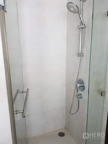 Condominium for rent or sale in Watthana, Bangkok - Glass-enclosed shower with handheld showerhead and light tiled walls.