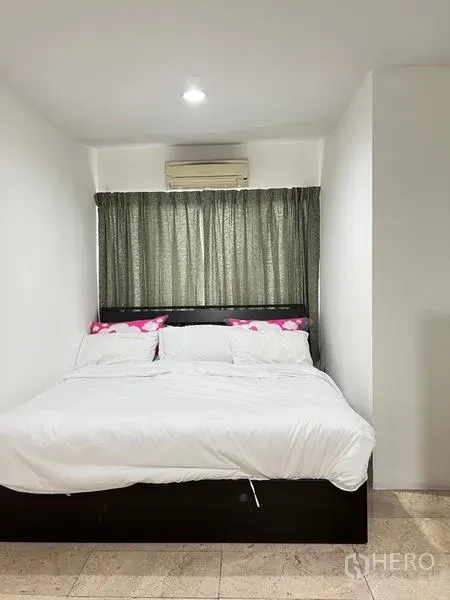 Condominium for rent in Ratchathewi, Bangkok - Compact bedroom with double bed, white linens and wall-mounted air conditioner.