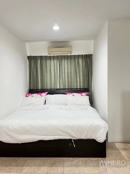 Condominium for rent in Ratchathewi, Bangkok - Compact bedroom with double bed, white linens and wall-mounted air conditioner.