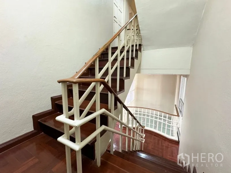 ทาวน์เฮาส์ ให้เช่าหรือขายในSuan Luang, Bangkok - บันไดไม้พร้อมราวเหล็กสีขาวภายในบ้านหลายชั้น