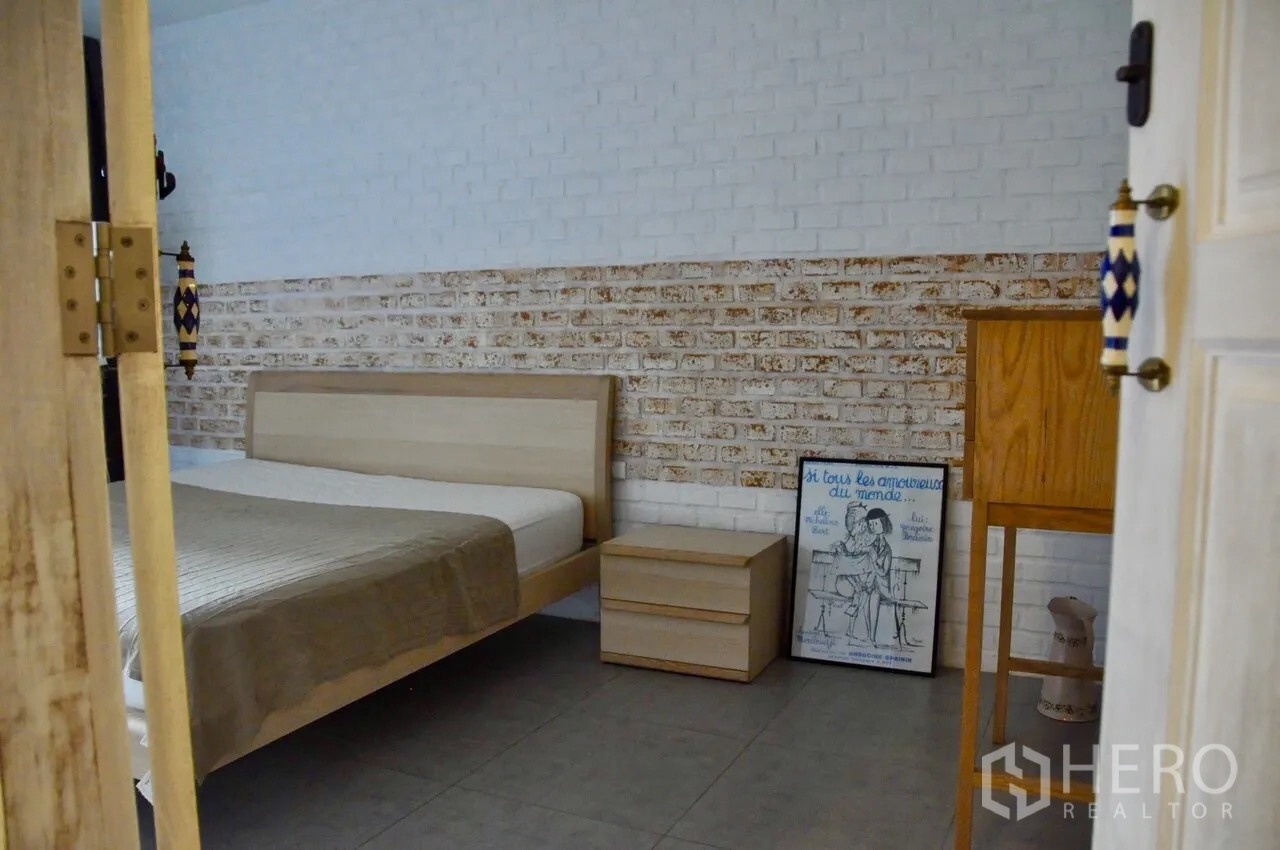 คอนโด ให้เช่าในBangkok - ห้องนอนบรรยากาศอบอุ่น เตียงไม้สีอ่อน โต๊ะข้างเตียง และผนังอิฐสองโทน