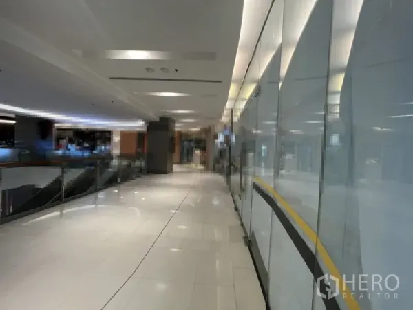 零售空间 出租在Khlong Toei, Bangkok - 采光良好的购物中心走廊，白色瓷砖地面、玻璃店面与金属栏杆