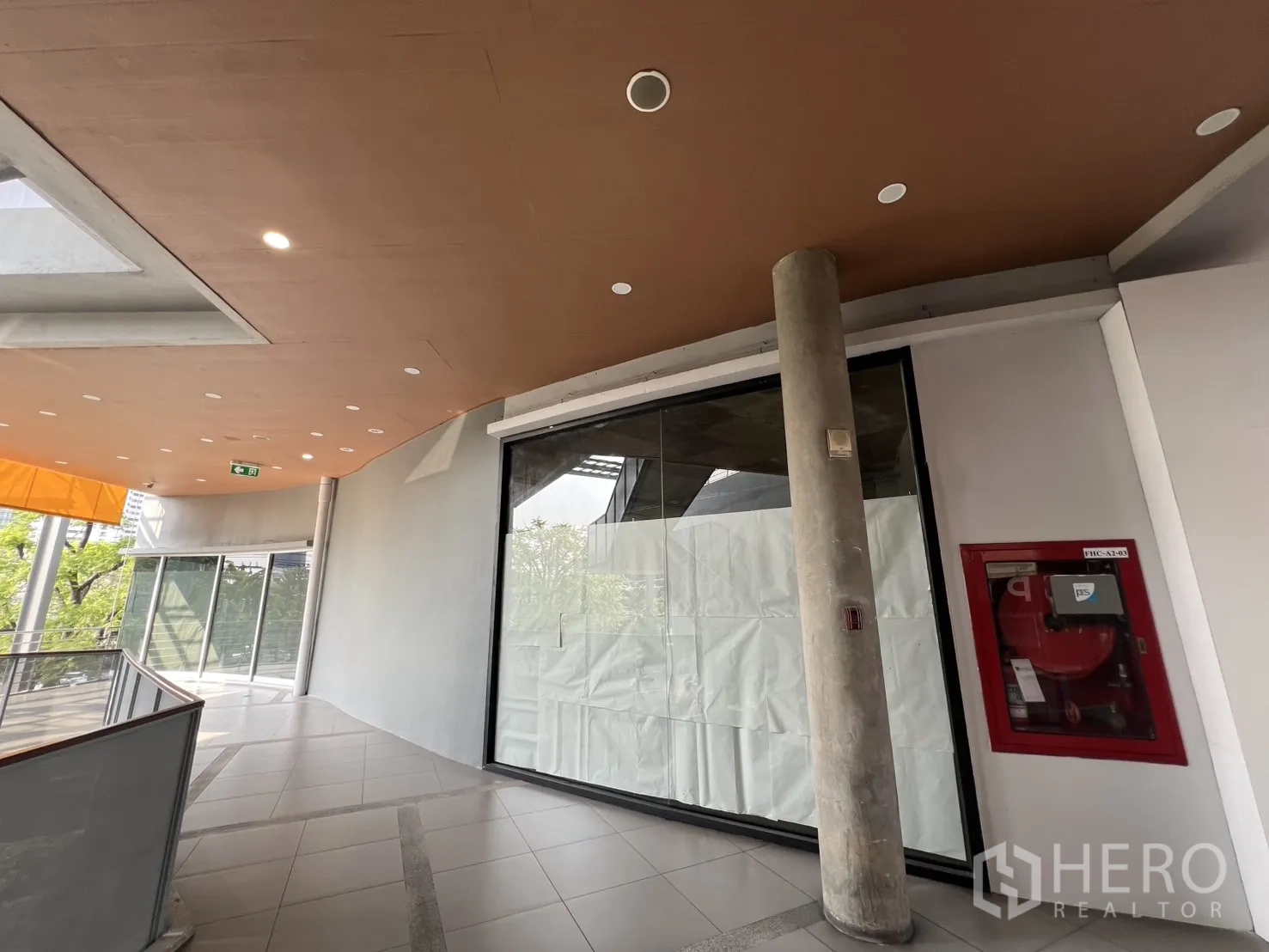 零售空间 出租在Khlong Toei, Bangkok - 弧形走廊与落地玻璃立面，旁有红色消防栓柜