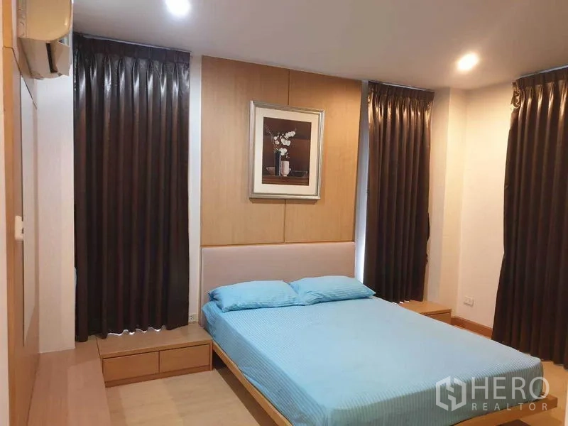 Condominium for rent in Watthana, Bangkok - Master bedroom with double bed, dark blackout curtains, wood paneling, and bedside storage.