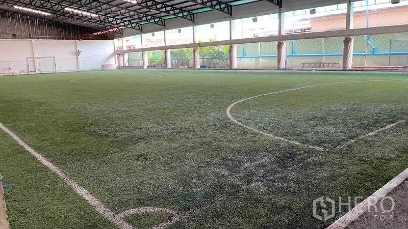 Warehouse for rent in Phra Pradaeng, Samut Prakan - Spacious covered artificial turf field with goalposts viewed from the side.