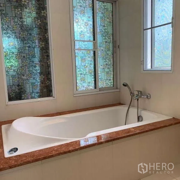 独立式住宅 出租在Lat Krabang, Bangkok - 浴室内置浴缸，配花纹磨砂窗。