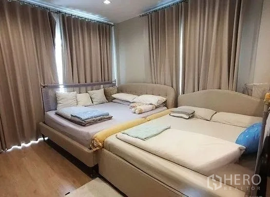 Detached House for rent in Don Mueang, Bangkok - Cozy bedroom with two beds, wood flooring and blackout curtains.