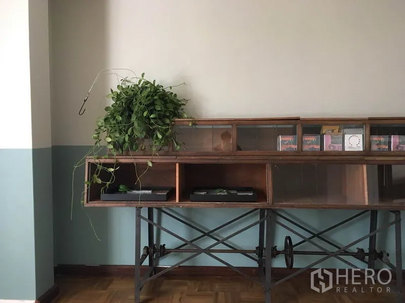 Apartment for rent in Khlong Toei, Bangkok - Vintage console display with potted plant against a half-painted green feature wall.