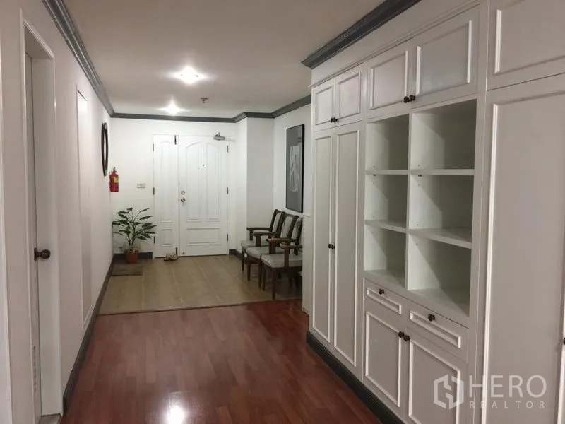 Condominium for rent in Watthana, Bangkok - Wide hallway with extensive white built-in storage, seating area and wood laminate floors.