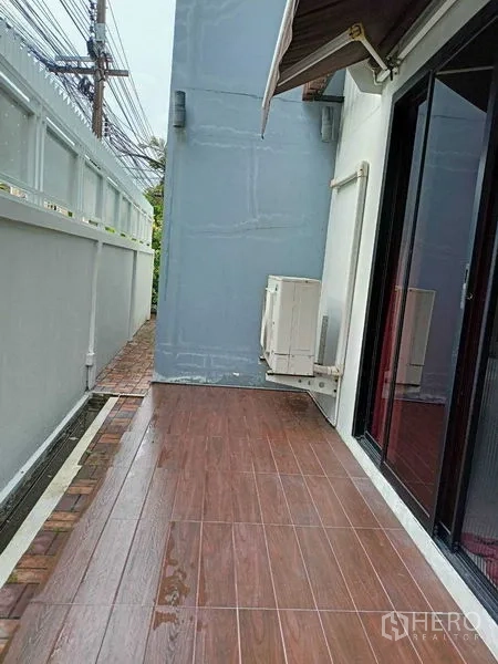Home Office for rent in Watthana, Bangkok - Narrow side terrace with wood-look tiles and outdoor AC unit.