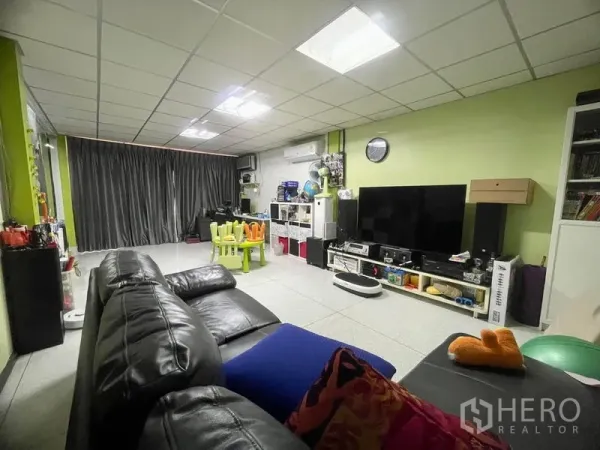 ทาวน์เฮาส์ ให้เช่าในSathon, Bangkok - ห้องนั่งเล่นกว้าง โซฟาหนังสีดำ ผนังทีวี และมุมเด็กเล่น