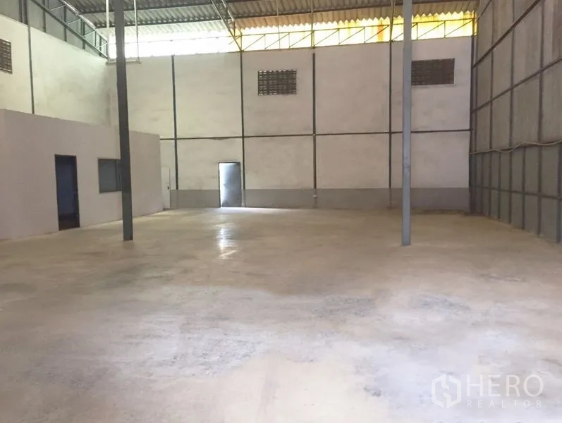 货栈 出租在Prawet, Bangkok - 开阔仓库地面，钢柱支撑、通风砖窗，并设后部出入口。