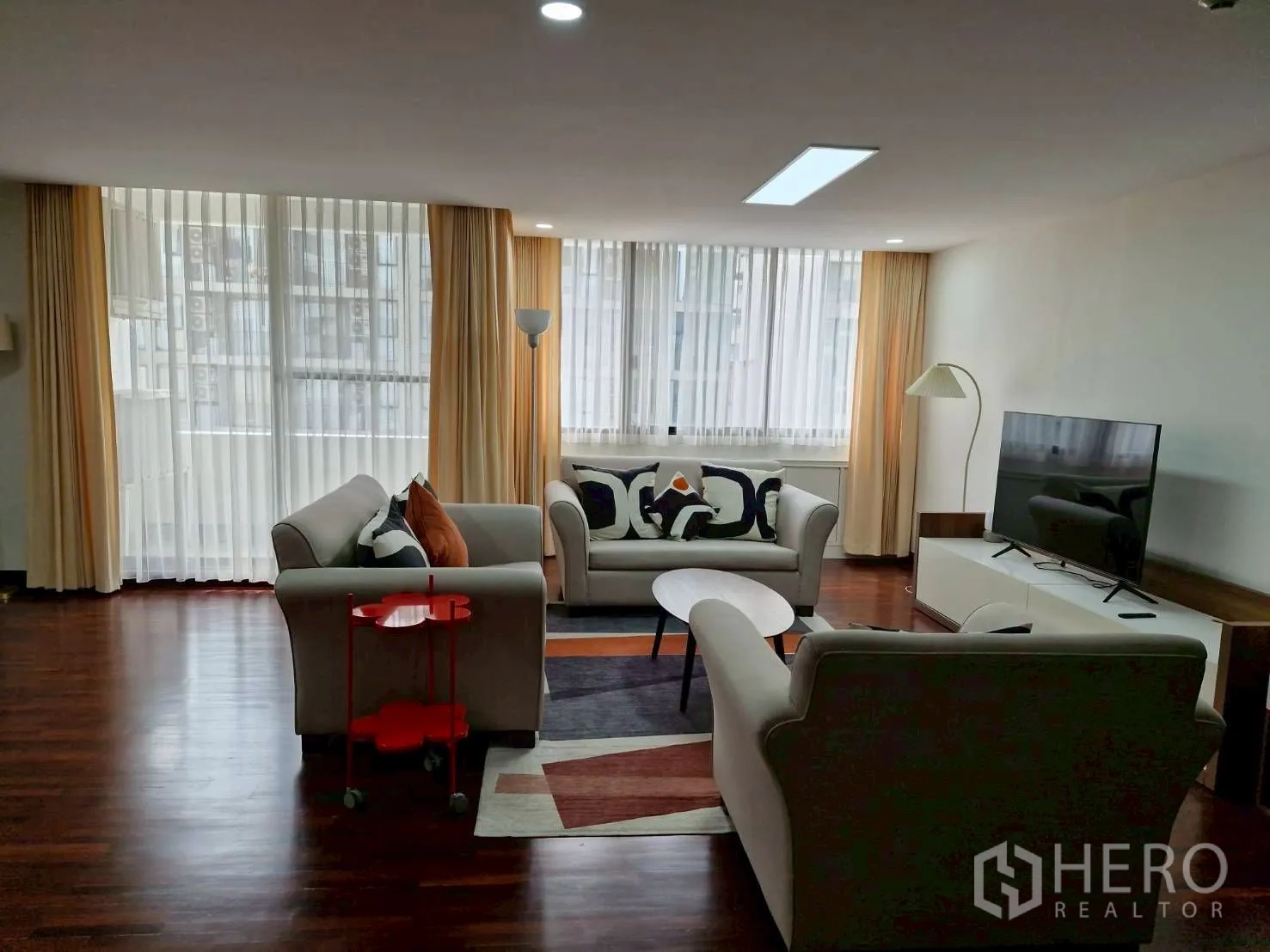 Condominium for rent in Khlong Toei, Bangkok - Long open-plan space with fluted-glass divider, track lights, dining set and cabinetry.