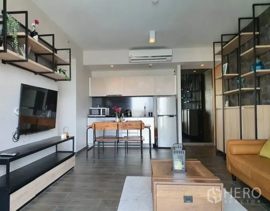 Condominium for rent or sale in Watthana, Bangkok - Open-plan living room with TV wall, dining table and modern kitchen in a bright Bangkok condo.