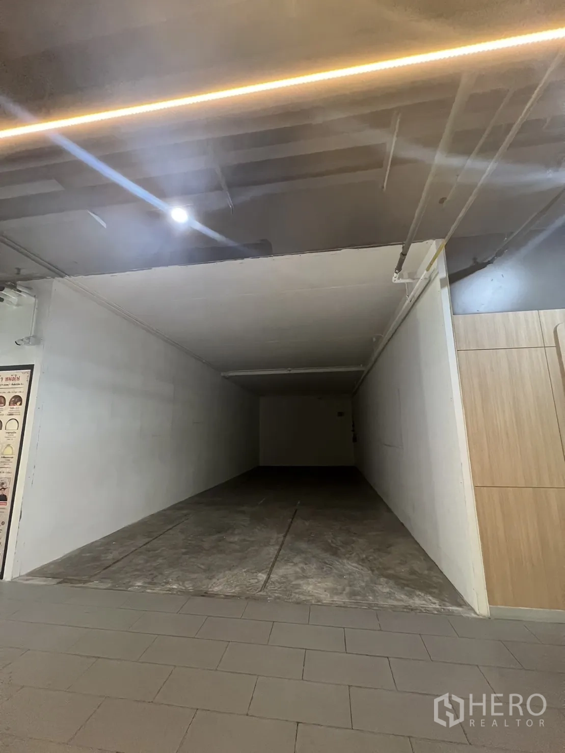 零售空间 出租在Watthana, Bangkok - 空置长方形商铺内景，白色墙面、混凝土地面、开放式顶棚，临室内走廊。