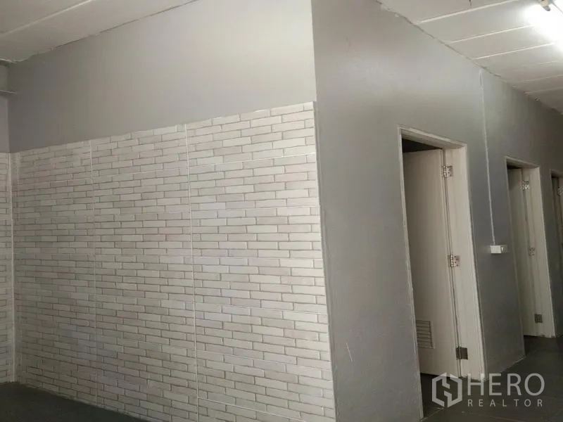 คลังสินค้า ให้เช่าในBang Phli, Samut Prakan - ผนังกระเบื้องลายอิฐสีขาว พร้อมประตูหลายบานเข้าสู่ห้องน้ำและพื้นที่เปลี่ยนชุด