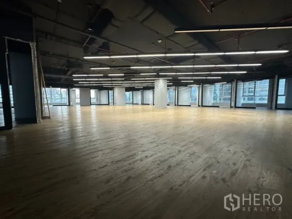 Office Space for rent in Bang Rak, Bangkok - Large office area with exposed ceiling, linear LED lights, and windows on multiple sides.