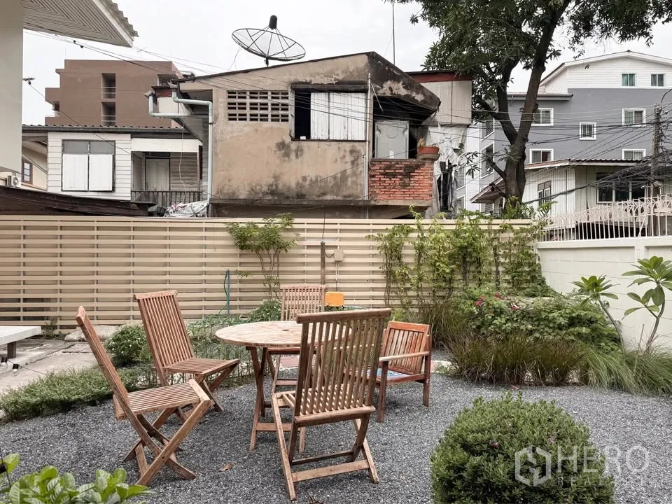 บ้าน ให้เช่าในHuai Khwang, Bangkok - ลานกรวดส่วนตัวพร้อมชุดโต๊ะเก้าอี้ไม้ท่ามกลางพุ่มไม้เขียว.