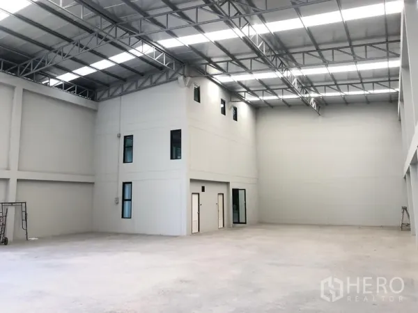 Factory for rent or sale in Bang Bua Thong, Nonthaburi - High-clear warehouse interior with steel truss roof and mezzanine office block.