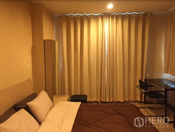 Condominium for rent in Bang Rak, Bangkok - Warm-toned bedroom with double bed, blackout curtains and a work desk.