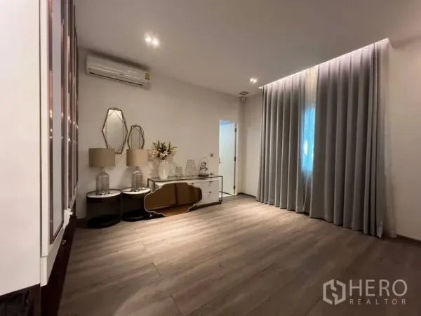 Detached House for rent or sale in Bang Phli, Samut Prakan - Cozy multi-purpose room with wood flooring, wall cabinets and long curtains.