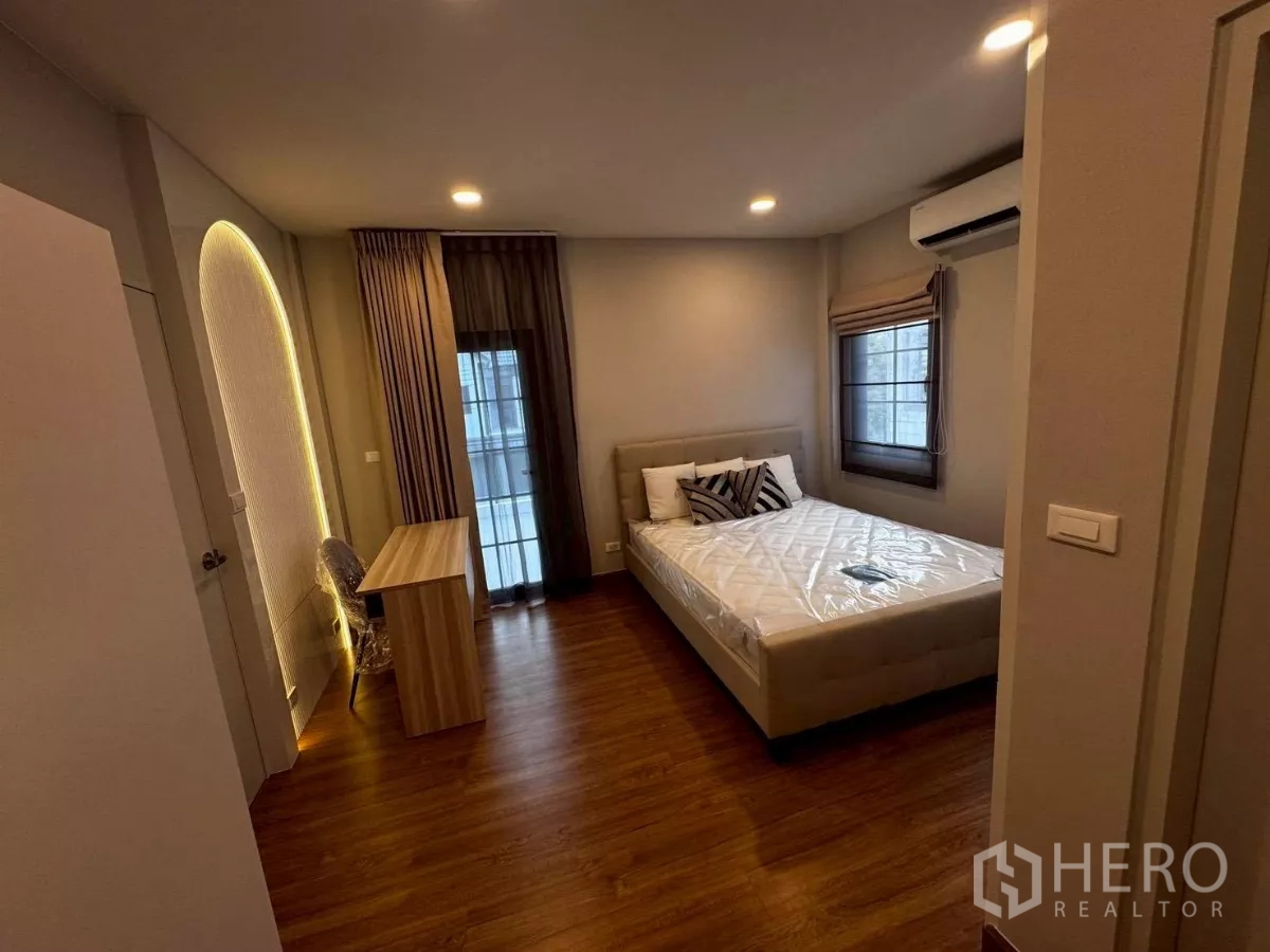 独立式住宅 出租在Bang Phli, Samut Prakan - 卧室配双人床与窗边书桌，灯光柔和并设空调。