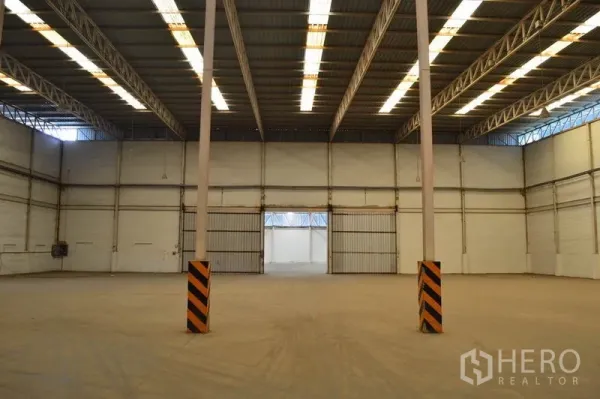 Warehouse for rent in Bang Sue, Bangkok - Open storage hall with central columns, bright roof panels and wide sliding gates for easy movement of goods.