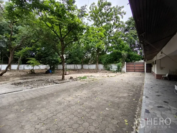 พื้นที่ขายปลีก ให้เช่าในWang Thonglang, Bangkok - ลานภายในรั้วพร้อมทางรถเข้าปูพื้นและต้นไม้ใหญ่ ข้างอาคารค้าปลีก