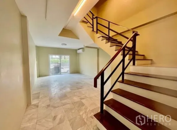 Townhouse for rent - Staircase with wooden handrail leading to an airy lounge area.