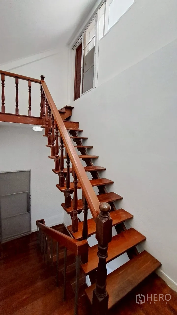 Townhouse for rent in Watthana, Bangkok - Wooden staircase with turned balusters leading to the upper floors.
