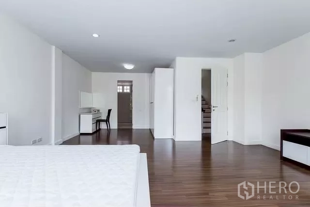 Townhouse for rent in Watthana, Bangkok - Primary bedroom with wood floors, wardrobes and generous space.