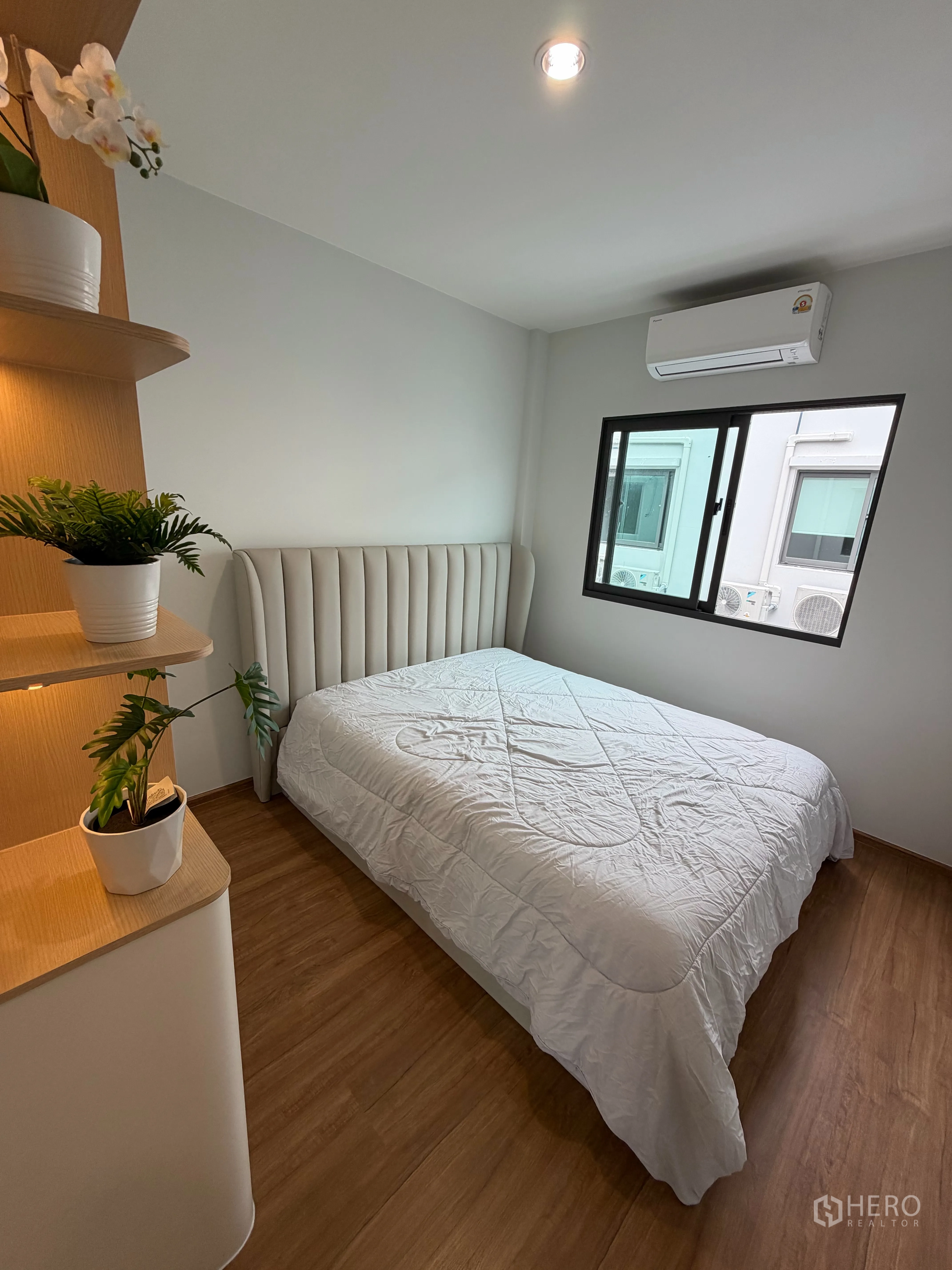 Townhouse for rent in Bang Phli, Samut Prakan - Cozy bedroom with bed, window, air conditioner and display shelves.