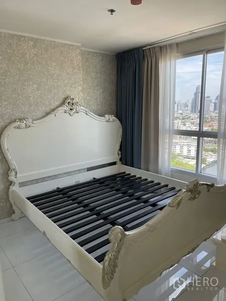 Condominium for sale in Suan Luang, Bangkok - Bedroom with ornate white bed frame, large window and panoramic Bangkok city views.