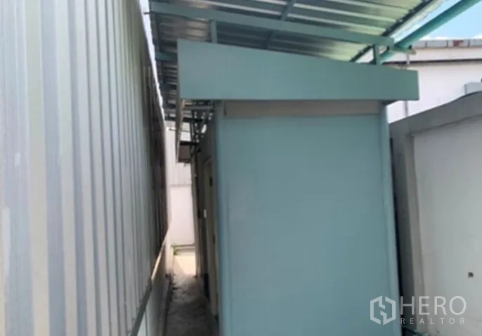 Warehouse for rent in Suan Luang, Bangkok - Covered side walkway beside the warehouse with a small utility or office annex.