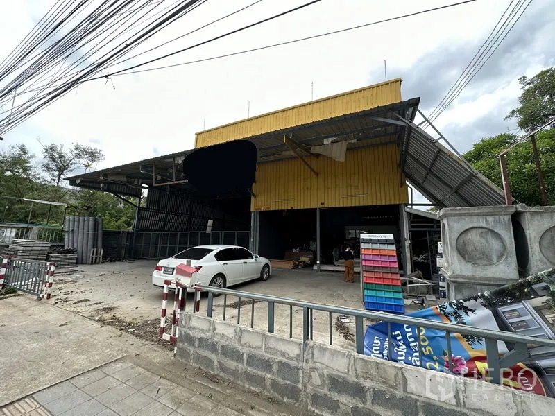 Warehouse for sale in Bang Khen, Bangkok - Angled exterior showing road-front warehouse with metal roof canopies and concrete driveway.
