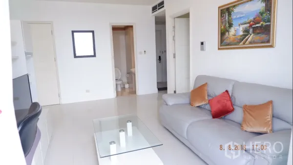 คอนโด ให้เช่าในKhlong Toei, Bangkok - ห้องนั่งเล่นสว่าง โซฟาสีเทา โต๊ะกลางกระจก และทางเข้าห้องน้ำ