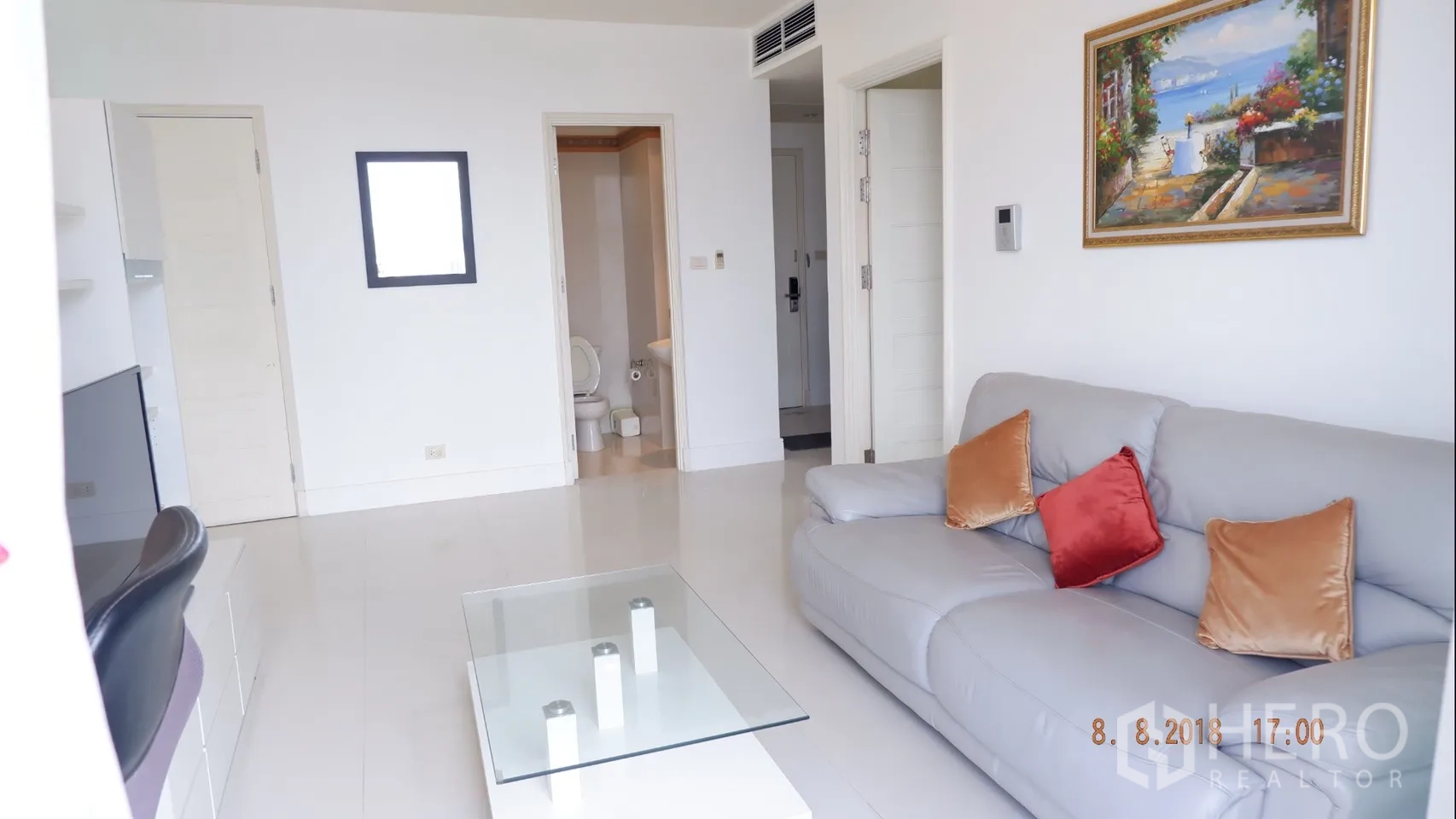 คอนโด ให้เช่าในKhlong Toei, Bangkok - ห้องนั่งเล่นสว่าง โซฟาสีเทา โต๊ะกลางกระจก และทางเข้าห้องน้ำ