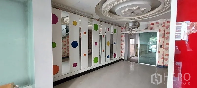 Home Office for sale in Wang Thonglang, Bangkok - Room with mirrored panels, colorful dots and chandelier beside a sliding door.