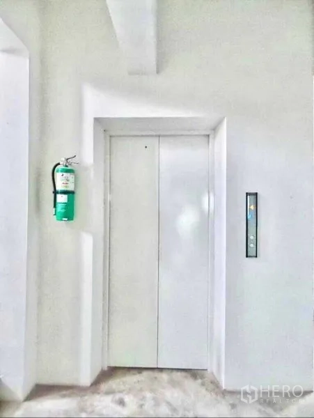 Office Space for rent or sale in Din Daeng, Bangkok - Close-up of a white elevator door with a wall-mounted fire extinguisher.