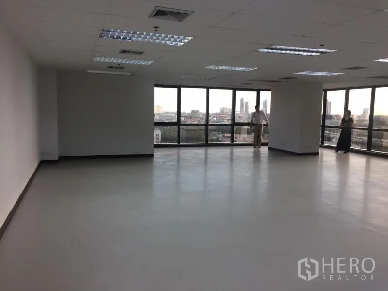 Office Space for rent in Bang Rak, Bangkok - Spacious unfurnished open‑plan office with large windows, city skyline views, drop ceiling lighting and air‑conditioning vents.