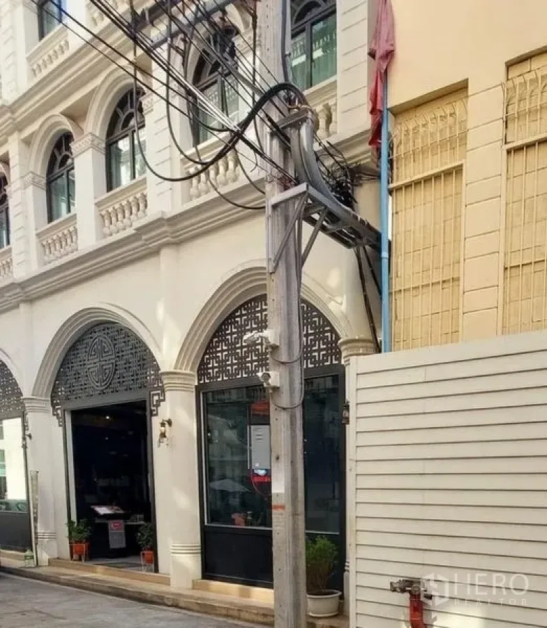 零售空间 出租在Watthana, Bangkok - 白色拱形立面，玻璃店面与几何装饰格栅。