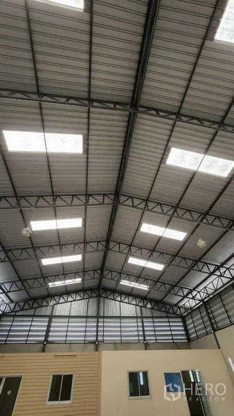 คลังสินค้า ให้เช่าในChon Buri - มุมมองใกล้ของโครงหลังคาและแผ่นสกายไลต์เหนือช่องหน้าต่างออฟฟิศ