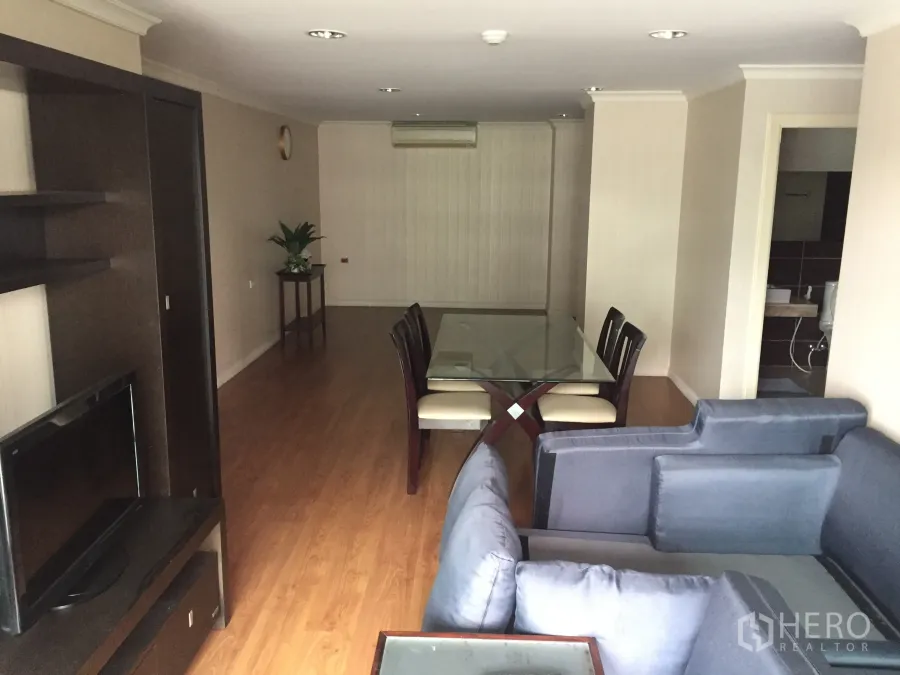 คอนโด ให้เช่าในWatthana, Bangkok - ห้องนั่งเล่นและรับประทานอาหารแบบโอเพ่นแปลน โซฟาสีเทา โต๊ะกระจกหกที่นั่ง ตู้วางทีวี และพื้นไม้