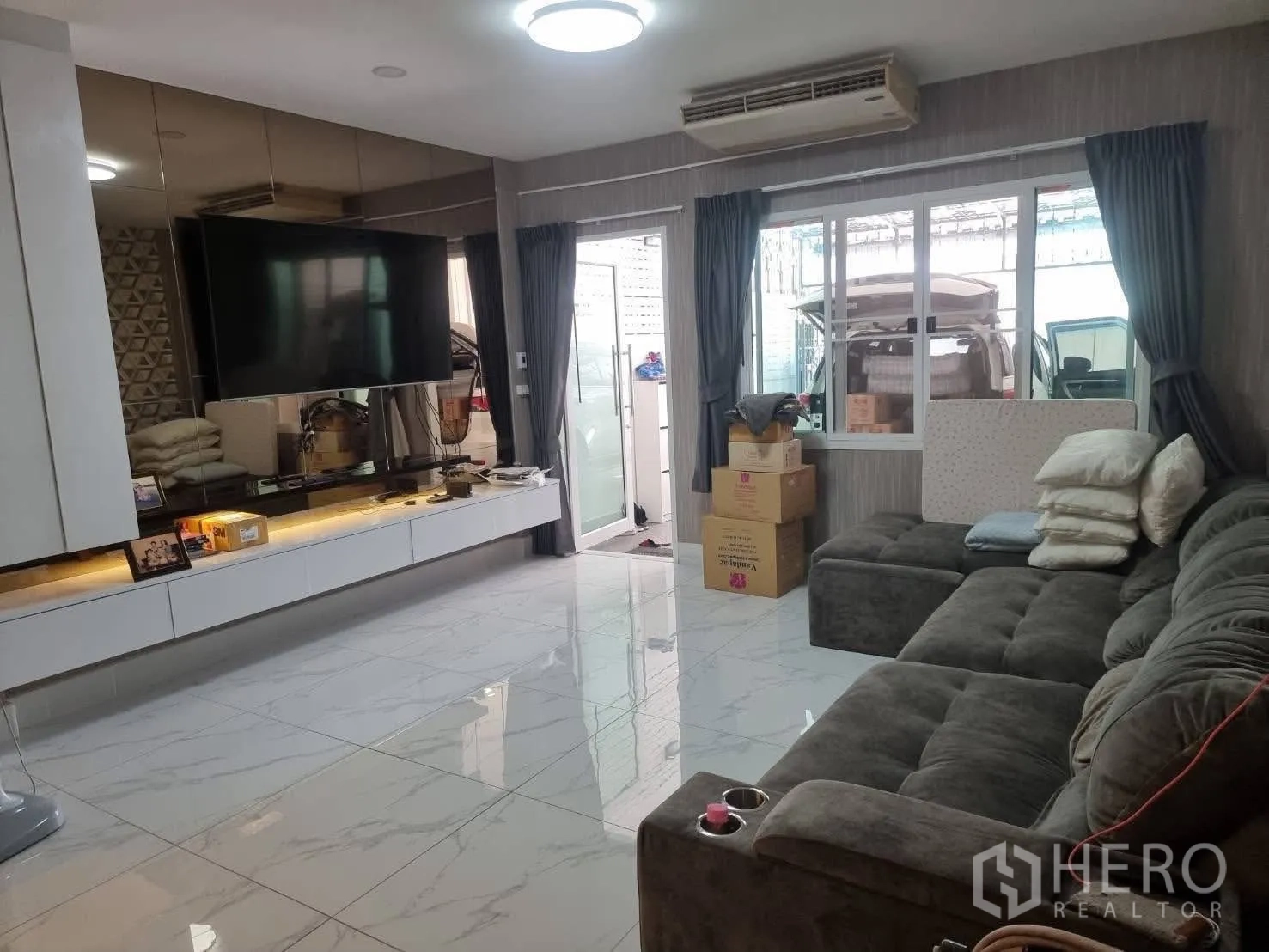 Townhouse for rent in Din Daeng, Bangkok - Living room with sectional sofa, large window and sliding door to outdoor area.