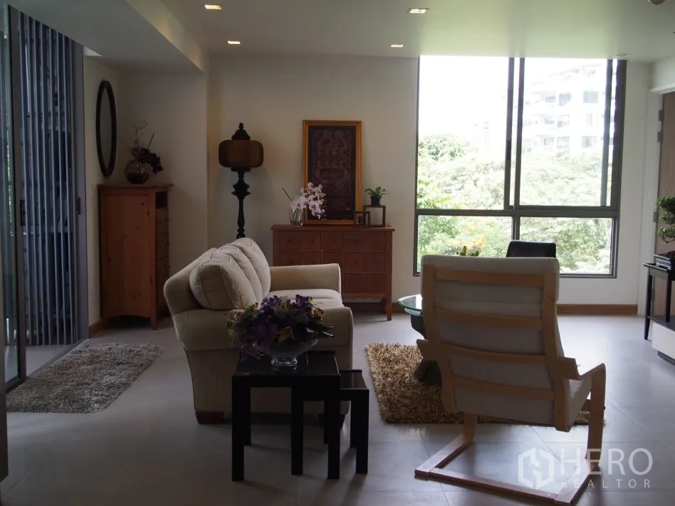 คอนโด for rent or sale in Watthana, Bangkok - ห้องนั่งเล่นสว่างพร้อมโซฟาและหน้าต่างบานใหญ่เห็นวิวต้นไม้