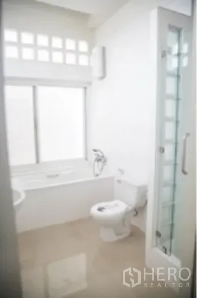 บ้าน ให้เช่าในKhlong Toei, Bangkok - ห้องน้ำโทนขาวพร้อมอ่างอาบน้ำ ตู้อาบน้ำกระจก และโถสุขภัณฑ์
