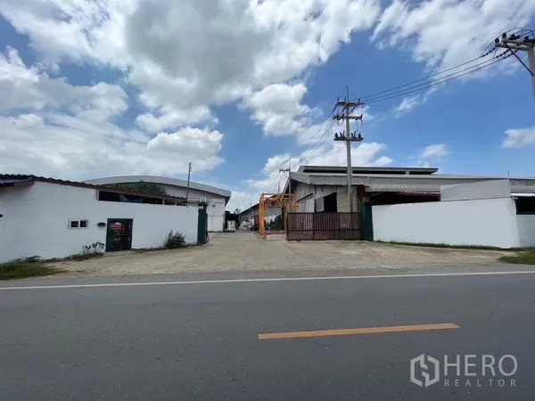 Warehouse for rent in Nakhon Chai Si, Nakhon Pathom - Street-front industrial compound with gated entrance, power lines, and multiple warehouse sheds in Nakhon Chai Si.