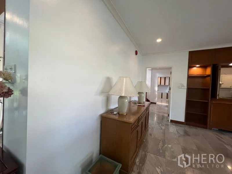 Detached House for rent in Bang Phli, Samut Prakan - Hallway corner with wooden sideboard, lamps, and built-in shelving beside the kitchen entrance.