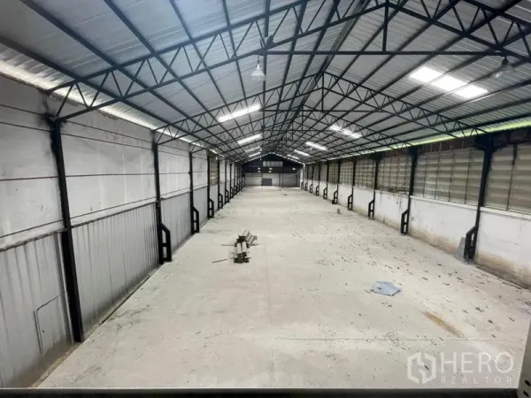 Factory for rent in Sam Khok, Pathum Thani - High-clearance warehouse hall with steel truss roof and ventilated side panels.