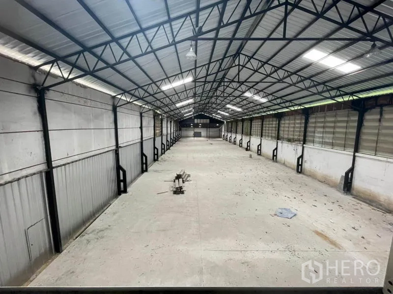 Factory for rent in Sam Khok, Pathum Thani - High-clearance warehouse hall with steel truss roof and ventilated side panels.
